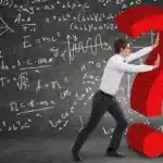 Student standing in front of a chalkboard filled with math formulas, thinking about SAT Math questions